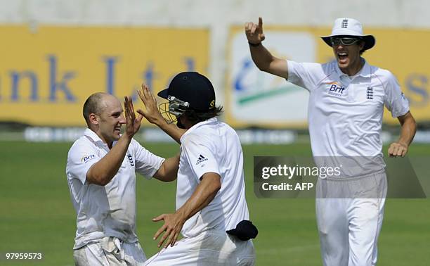 England cricket team captain Alastair Cook celebrates with teammatea James Tredwell and Steven Finn after the dismissal of unseen Bangladeshi batsman...