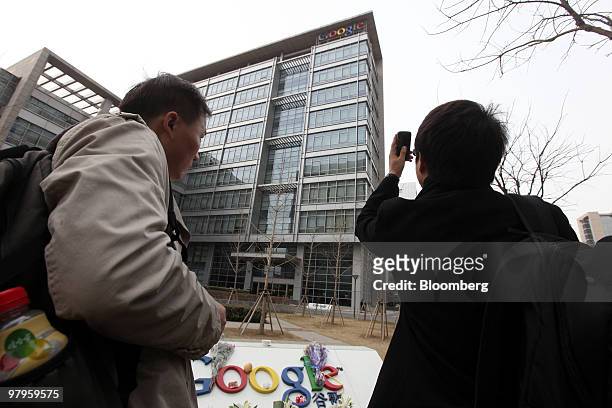 People take photographs of the Google Inc. Sign outside the company's offices in Beijing, China, on Tuesday, March 23, 2010. Google Inc., following...
