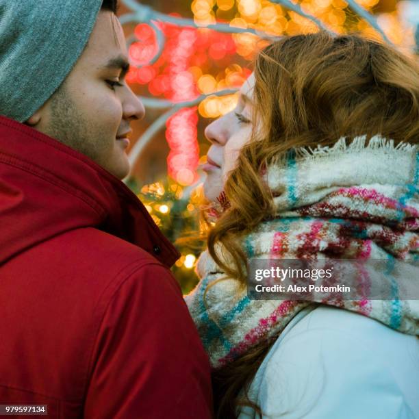 la coppia amante interrazziale, gli adolescenti, la bellissima ragazza dai capelli lunghi bianca caucasica di 17 anni e il bel ragazzo ispanico latino-ispanico di 18 anni, guardando le luci di natale e divertendosi nella fredda giornata invernale a brookly - 18 19 years photos foto e immagini stock