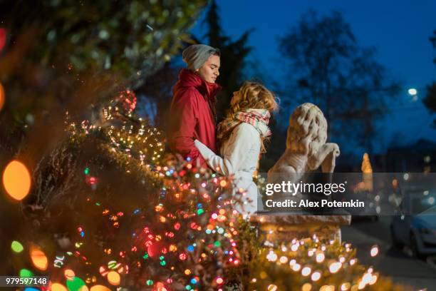 the interracial loving couple, teenagers, the beautiful caucasian white 17-years-old long haired girl and handsome latino hispanic 18-years-old boy, hugs surrounded by christmas lights  and having fun in the cold winter day in brooklyn, new york - 18 19 years stock pictures, royalty-free photos & images