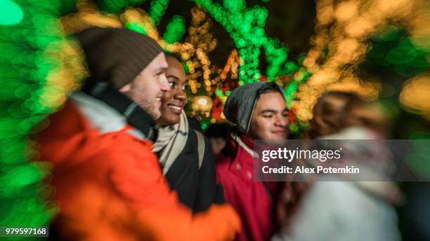 de groep van jonge vrienden, omvatten de inter-raciale paar zwart mooie vrouw en kaukasische witte knappe man en tieners, genieten van kerstverlichting in brooklyn - black christmas stockfoto's en -beelden