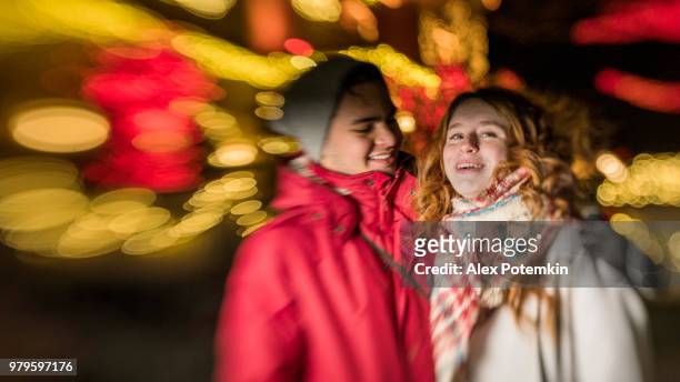 the interracial loving couple, teenagers, the beautiful caucasian white 17-years-old long haired girl and handsome latino hispanic 18-years-old boy, watching christmas lights  and having fun in the cold winter day in brooklyn, new york - alex potemkin or krakozawr stock pictures, royalty-free photos & images