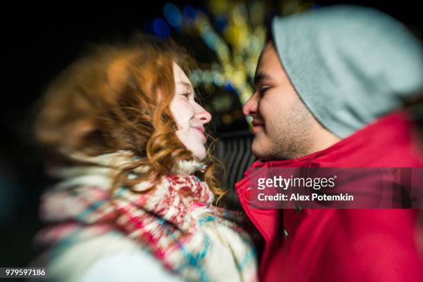 the interracial loving couple, teenagers, the beautiful caucasian white 17-years-old long haired girl and handsome latino hispanic 18-years-old boy, watching christmas lights  and having fun in the cold winter day in brooklyn, new york - alex potemkin or krakozawr stock pictures, royalty-free photos & images