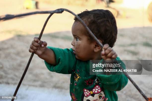 Syrian child from the northern city of Manbij, displaced by fighting between the Syrian Democratic Forces and Islamic State group fighters, plays...