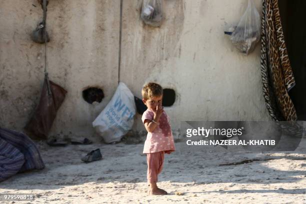 Syrian child from the northern city of Manbij, displaced by fighting between the Syrian Democratic Forces and Islamic State group fighters, stands...