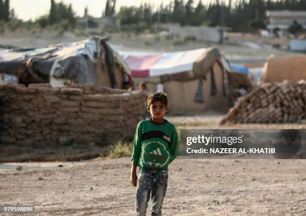 Syrian child from the northern city of Manbij, displaced by fighting between the Syrian Democratic Forces and Islamic State group fighters, stands...