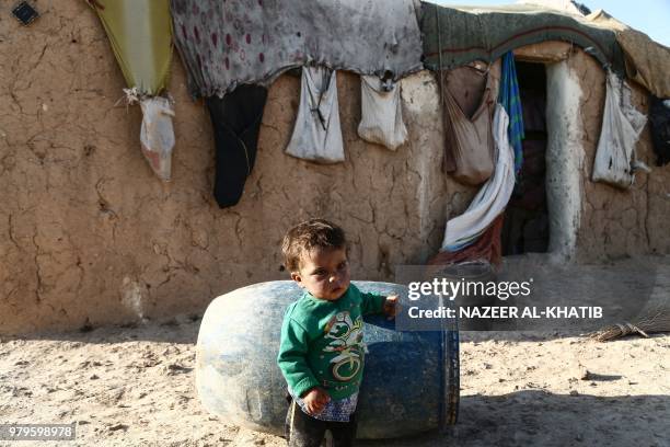 Syrian child from the northern city of Manbij, displaced by fighting between the Syrian Democratic Forces and Islamic State group fighters, stands...