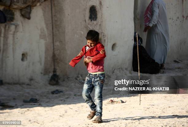 Syrian child from the northern city of Manbij, displaced by fighting between the Syrian Democratic Forces and Islamic State group fighters, puts on a...