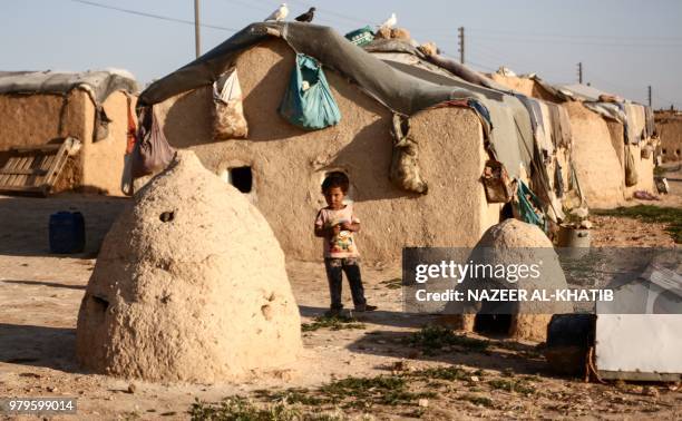 Syrian child from the northern city of Manbij, displaced by fighting between the Syrian Democratic Forces and Islamic State group fighters, stands...