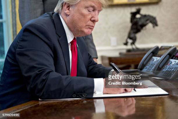 President Donald Trump signs an executive order to end family separations at the border in the Oval Office of the White House in Washington, D.C.,...