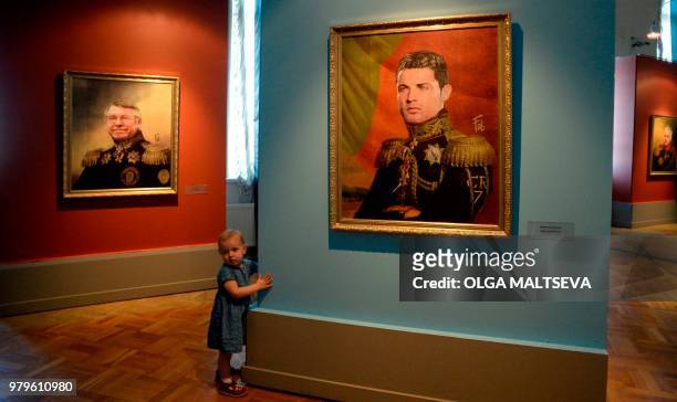 Child walks in front of portraits of Manchester United's former Scottish Manager Sir Alex Ferguson and Portugal football player Cristiano Ronaldo as...