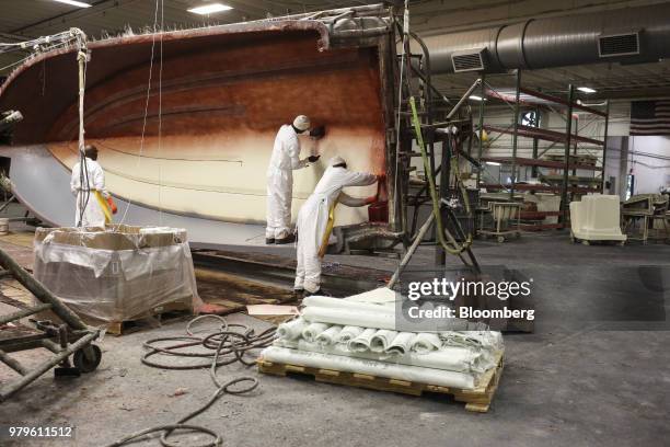Workers apply layers of fiber glass to a hull at the Winnebago Industries Inc. Chris-Craft boat manufacturing facility in Sarasota, Florida, U.S., on...