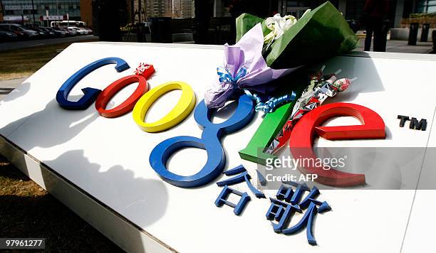 Bouquet of flowers lies on the Google logo outside the company's China head office in Beijing on March 23, 2010 after the US web giant said it would...