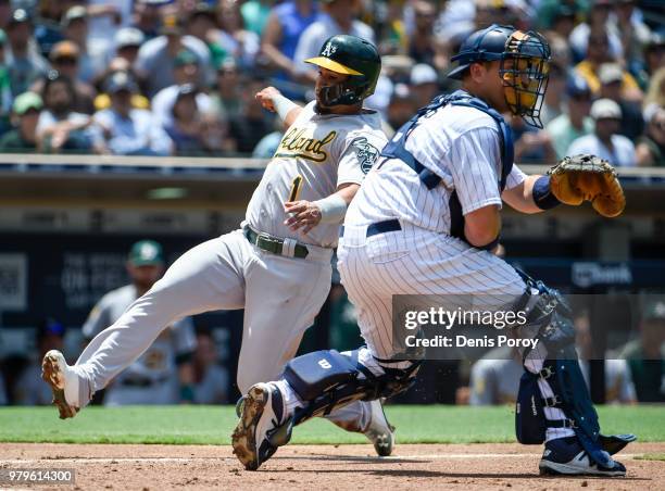 Franklin Barreto of the Oakland Athletics scores ahead of the throw to A.J. Ellis of the San Diego Padres during the third inning of a baseball game...