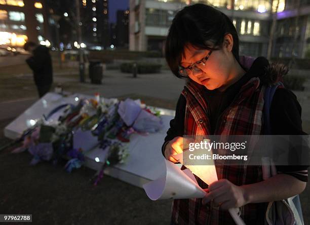 Woman lights a candle outside the Google Inc. Offices in Beijing, China, on Tuesday, March 23, 2010. Google Inc., following through on a pledge to...