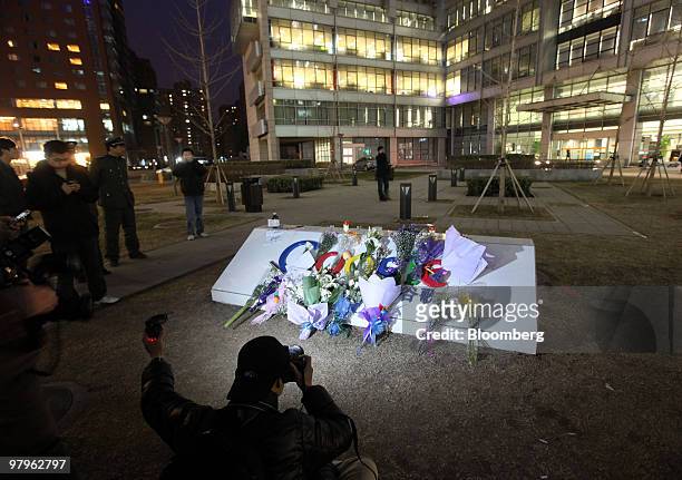 Photographers take pictures of the flowers collecting outside the Google Inc. Offices in Beijing, China, on Tuesday, March 23, 2010. Google Inc.,...