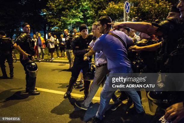 Man is being arrested by riot police in front of the prime minister's office in Bucharest on June 20, 2018 during a protest against corruption and...