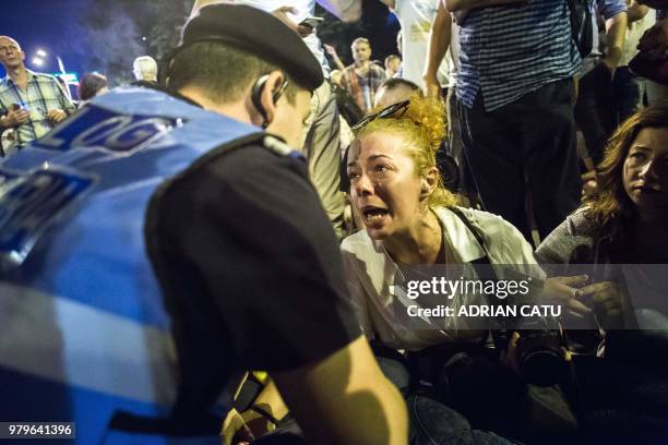 Demonstrator reacts in front of a riot police officer in Bucharest on June 20, 2018 during a protest in front of the prime minister's office against...
