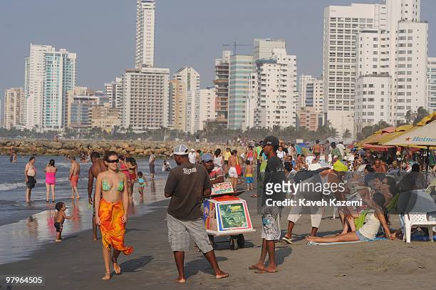 Of INDIAS, COLOMBIA People spend a weekend day at the beach. In the background old Cartagena architecture and modern buildings are visible. Cartagena...