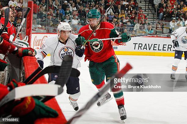 Guillaume Latendresse of the Minnesota Wild checks Marc Pouliot of the Edmonton Oilers during the game at the Xcel Energy Center on March 16, 2010 in...