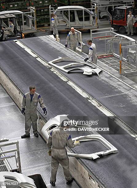 Employees of German car manufacturer Volkswagen take side parts of car bodies from an assembly line on March 8, 2010 in Wolfsburg, northern Germany....