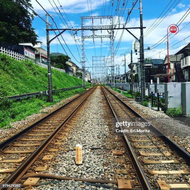cityscape with straight train tracks, lush foliage and blue sky. - ota ward stock-fotos und bilder