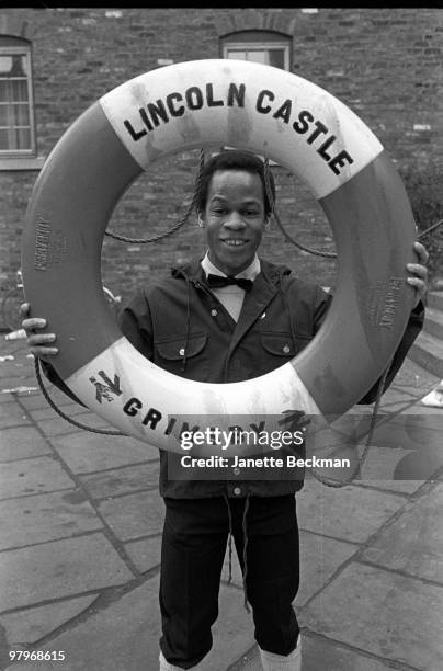 Portrait of American musician Blair Cunningham from the pop group Haircut 100 as he holds up, and looks through, a lifebuoy, labelled 'Lincoln...