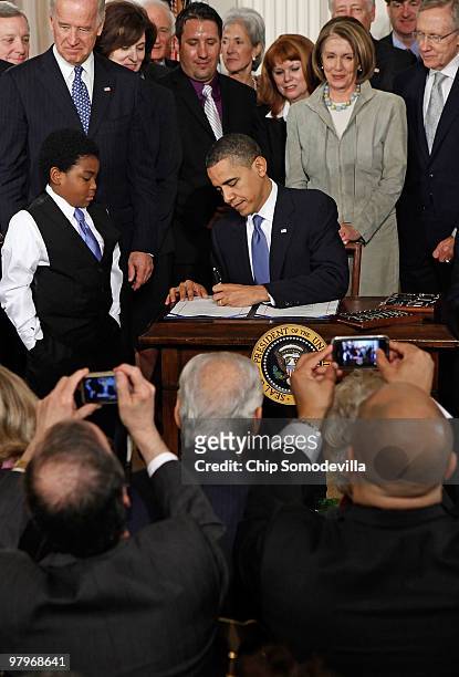 Members of the House of Representatives take photographs with their phones as President Barack Obama signs the Affordable Health Care for America Act...