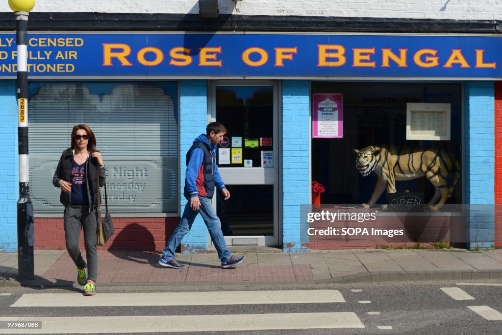 People walk past an Indian restaurant in the town centre of...