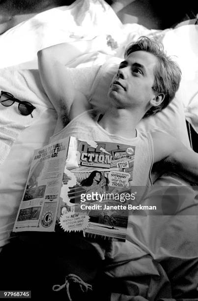 Portrait of British musician Nick Heyward from the pop group Haircut 100 as he lies in bed on his back, an copy of '10-4 Action open on his chest,...