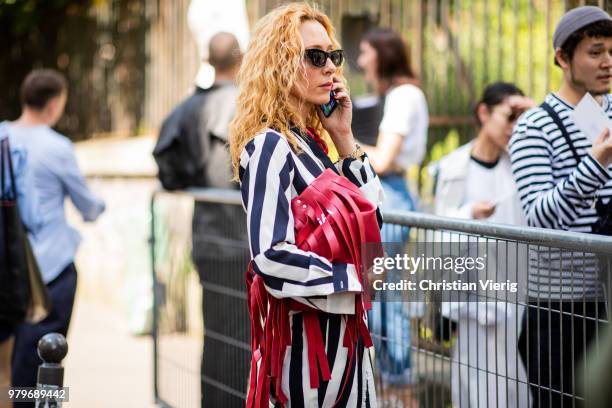 Elina Halimi wearing red bag with fringes, black white striped suit while calling on the phone is seen outside Y/PROJECT on day two of Paris Fashion...