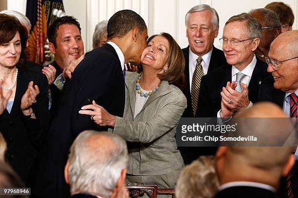 President Barack Obama kisses Speaker of the House Nancy Pelosi after signing the Affordable Health Care for America Act during a ceremony with...