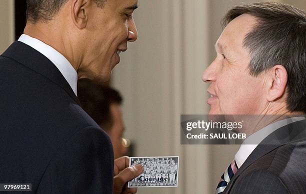 President Barack Obama holds a paper that says "courage" given to him by Ohio Democratic Representative Dennis Kucinich after signing the healthcare...