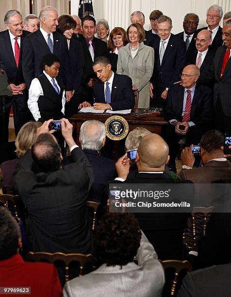 Members of the House of Representatives take photographs with their phones as President Barack Obama signs the Affordable Health Care for America Act...