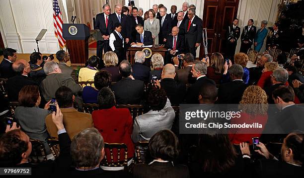 President Barack Obama signs the Affordable Health Care for America Act during a ceremony with fellow Democrats in the East Room of the White House...