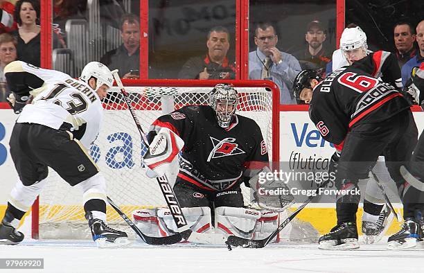 Justin Peters of the Carolina Hurricanes keeps his eye on the puck as teammate Tim Gleason attempts to clear away from Bill Guerin of the Pittsburgh...