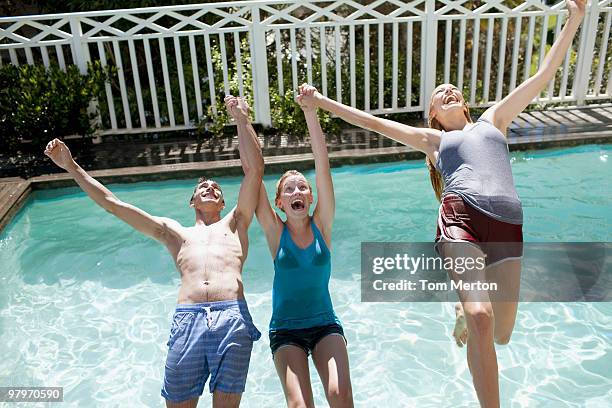 friends holding hands and falling backwards into swimming pool - falling behind stock pictures, royalty-free photos & images