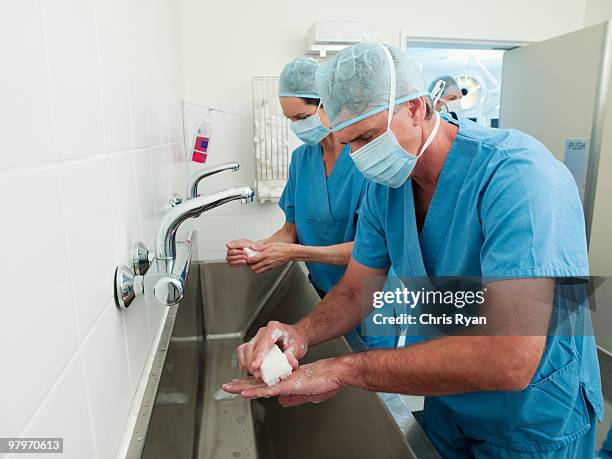 surgeons in scrubs washing hands at sink - hospital safety stock pictures, royalty-free photos & images