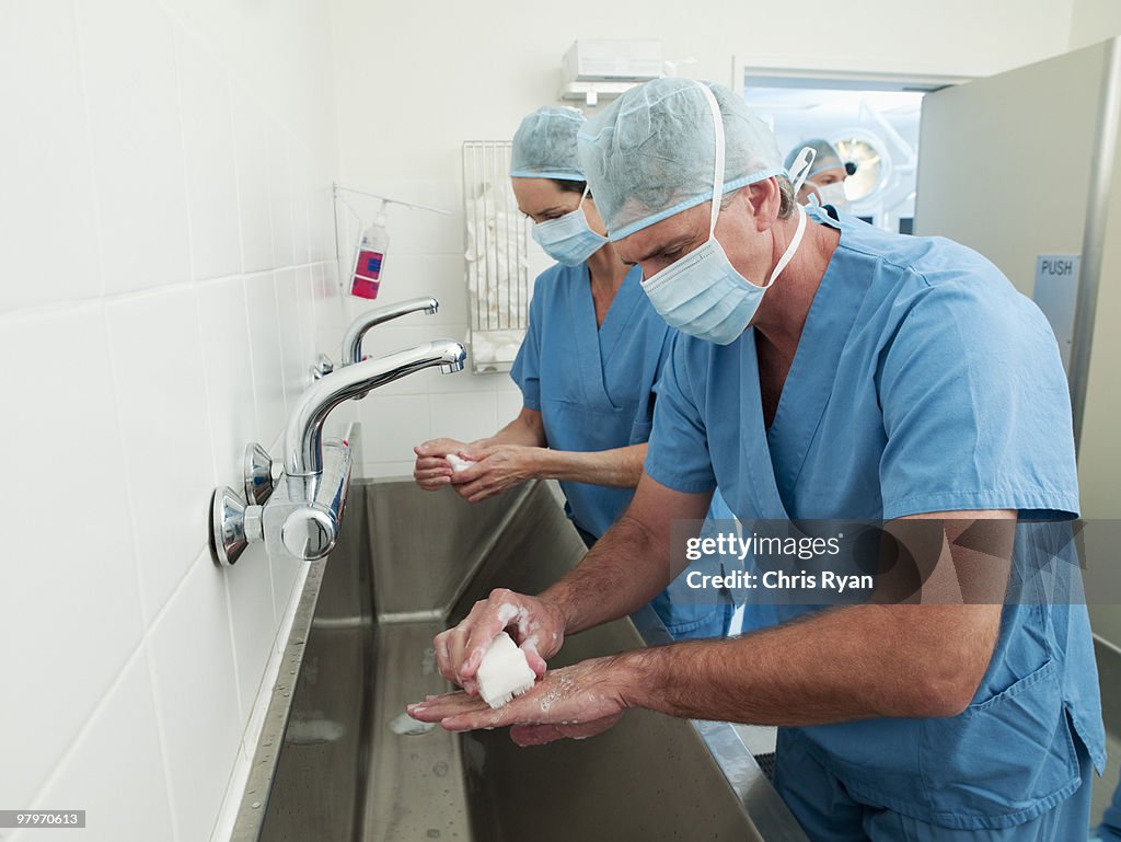 Surgeons in scrubs washing hands at sink