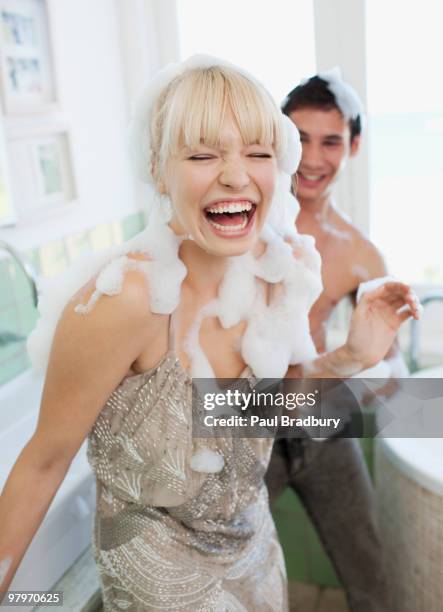 couple covered with soap suds in bathroom - woman cleaning for man stock pictures, royalty-free photos & images