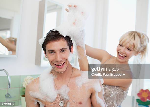 woman playing with soap suds on man in bathroom - messy boyfriend stock pictures, royalty-free photos & images