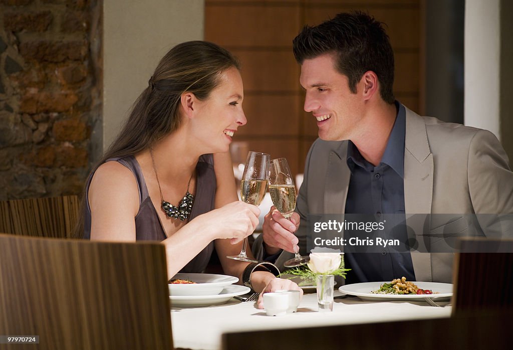 Couple toasting champagne glasses at restaurant table