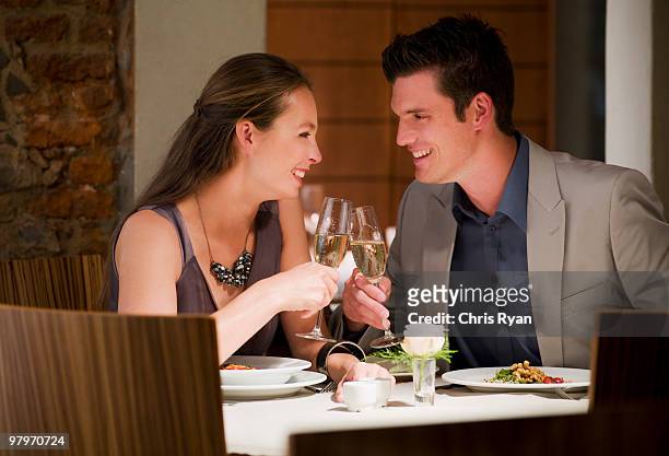 couple toasting champagne glasses at restaurant table - evening meal restaurant stock pictures, royalty-free photos & images