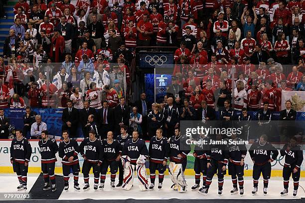 Dejected Team USA players wait to receive their silver medals following their 3-2 overtime defeat in the ice hockey men's gold medal game between USA...