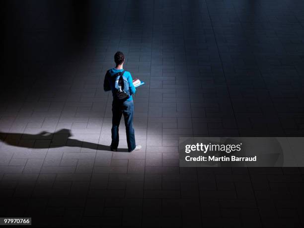 macho estudiante con mochila y libros en cuarto oscuro - man holding book fotografías e imágenes de stock