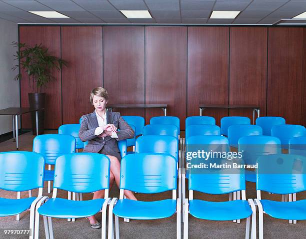 businesswoman checking wristwatch in empty conference room - impatient stock pictures, royalty-free photos & images