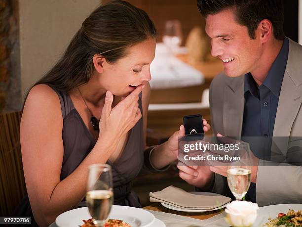 man surprising woman with engagement ring at restaurant table - man proposing indoor stock pictures, royalty-free photos & images