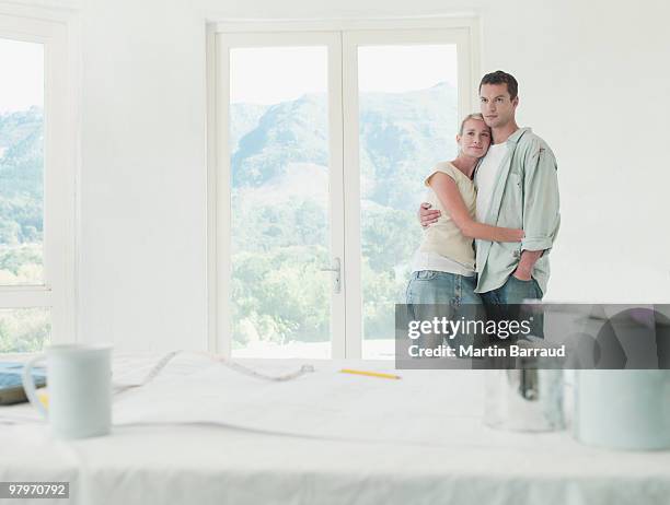 couple hugging in room with drop cloths and paint cans - french doors stockfoto's en -beelden