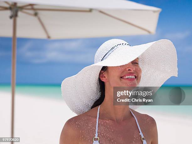 woman wearing sun hat on beach - protection luxe stock-fotos und bilder