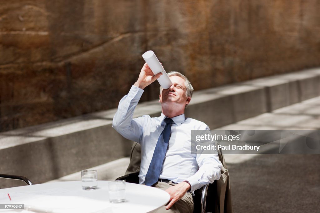 Businessman looking up through rolled up paperwork